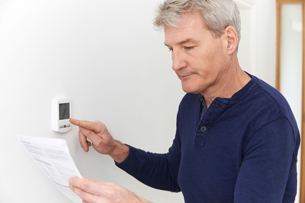 St. Louis man adjusting thermostat